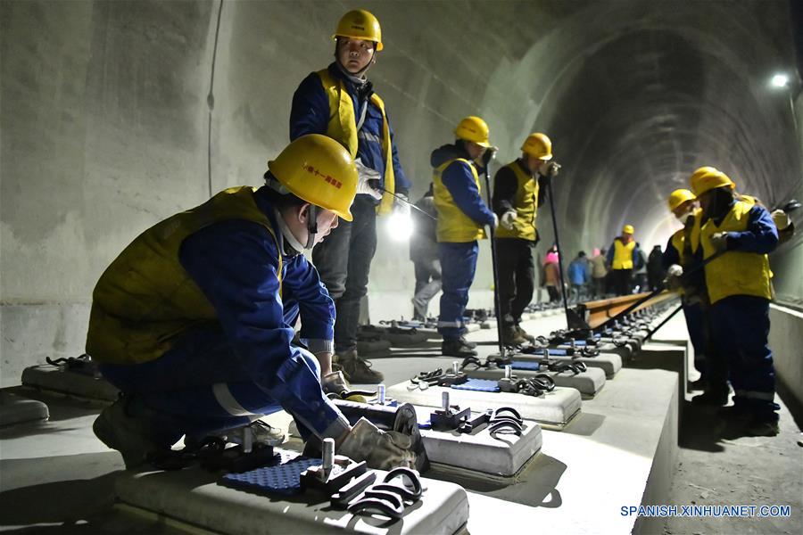 China: Trabajadores colocando un largo riel de acero para la línea ferroviaria Lhasa-Nyingchi